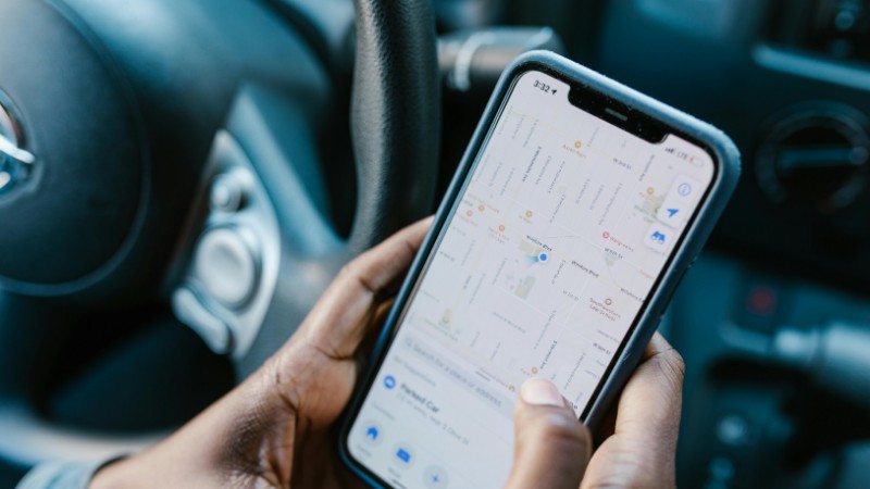 Close-up of hands holding a smartphone with GPS navigation displayed, in a car setting., tags: con di - pexel